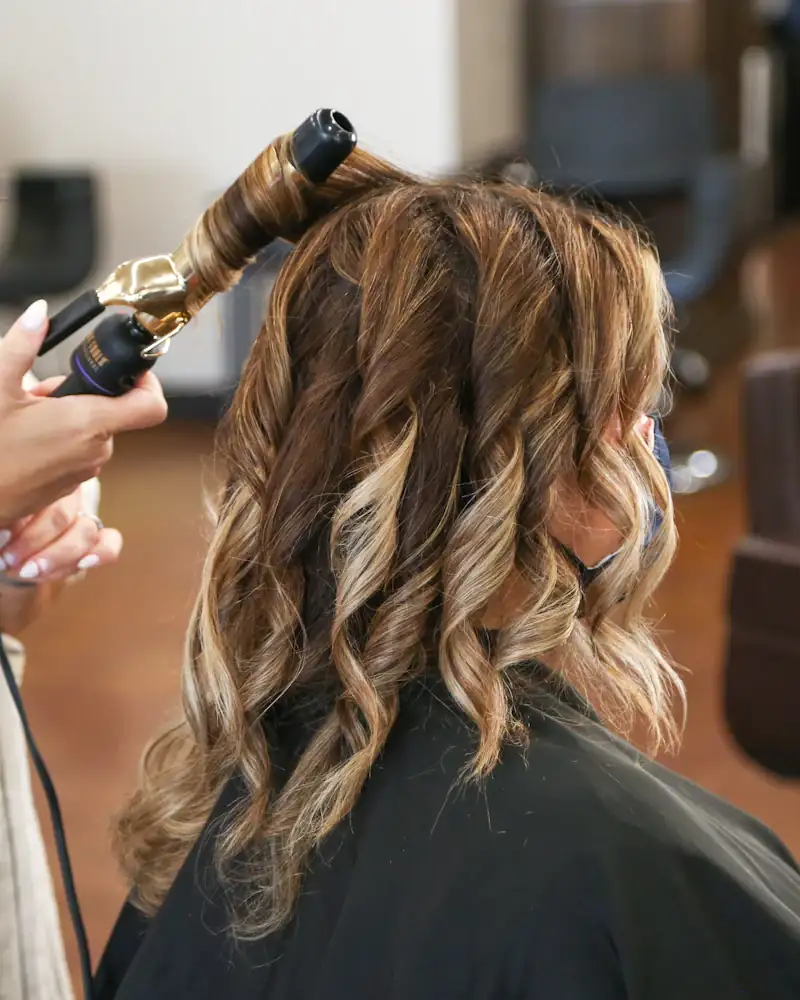 Cabelo castanho em ondas sendo finalizado com babyliss